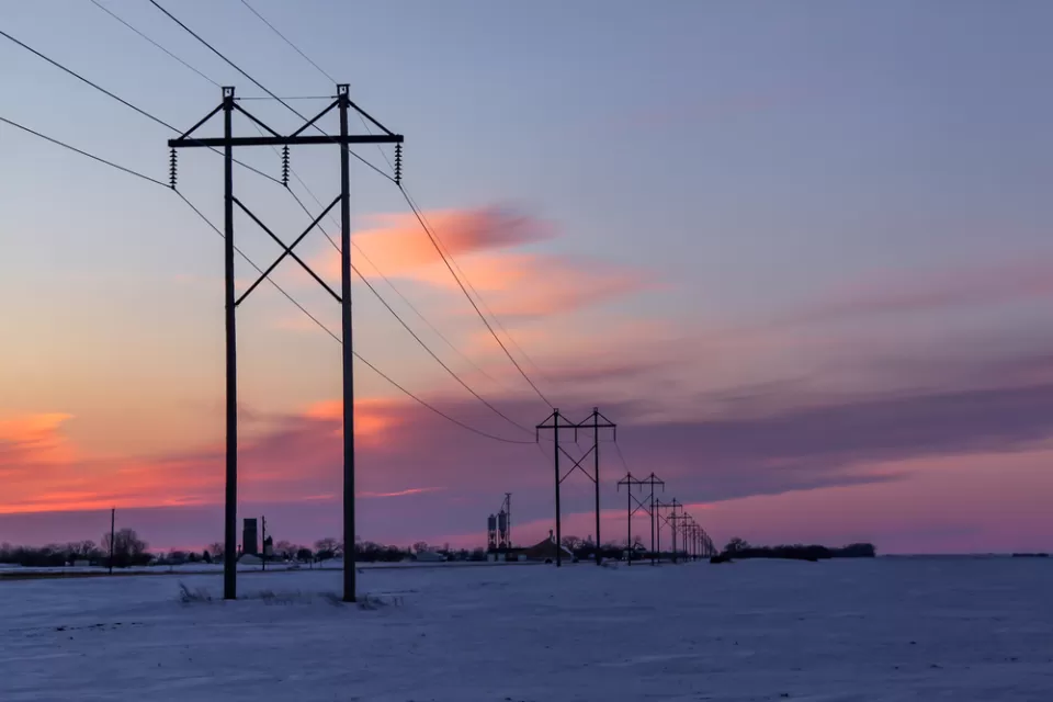 Power lines against sunset sky and snowy landscape in rural Minnesota